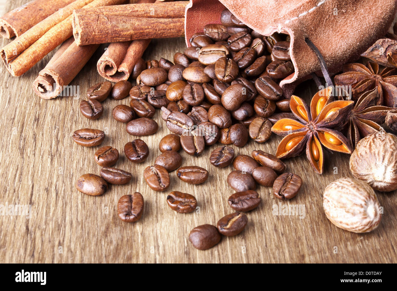 Les grains de café aux épices sont dispersés sur fond de bois Banque D'Images