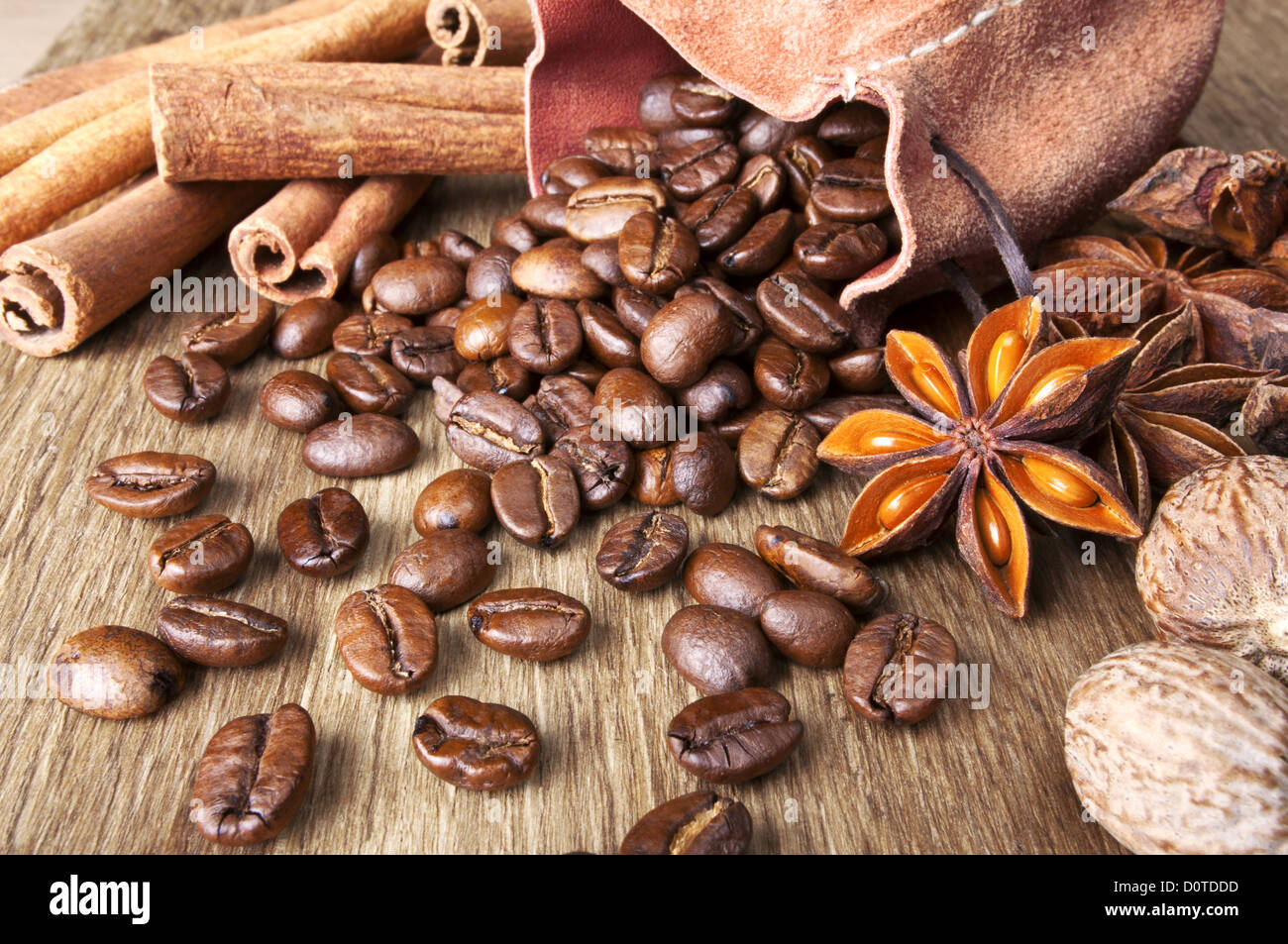 Les grains de café aux épices sont dispersés sur fond de bois Banque D'Images