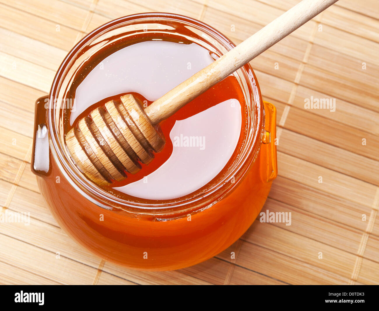 Pot de miel en verre avec un drizzler sur bambou Banque D'Images