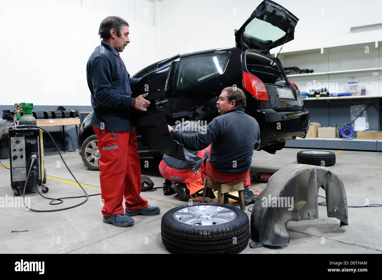 Trois mécaniciens travaillant dans un garage auto Banque D'Images