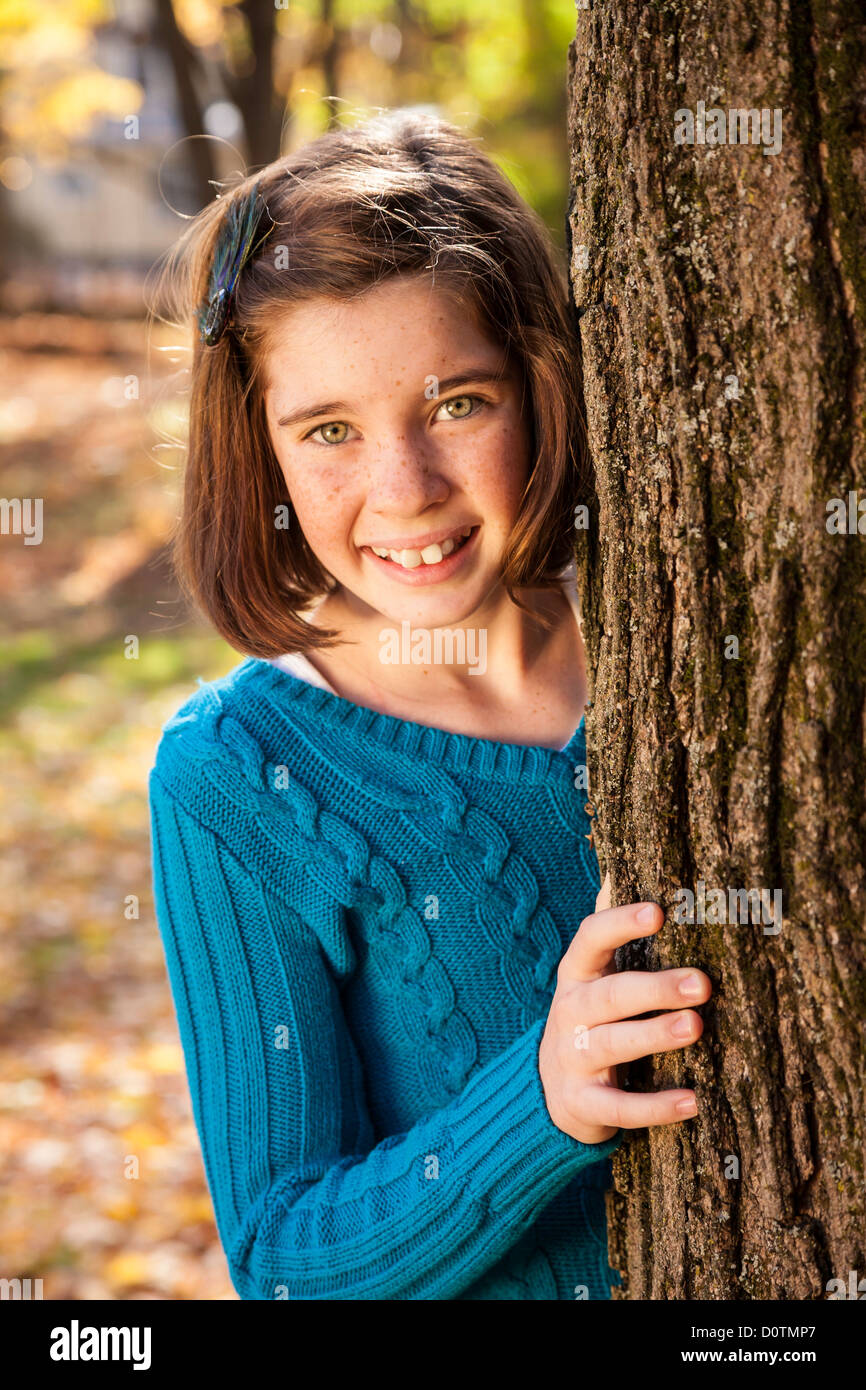 Young Girl Peeking autour d'arbre, USA Banque D'Images