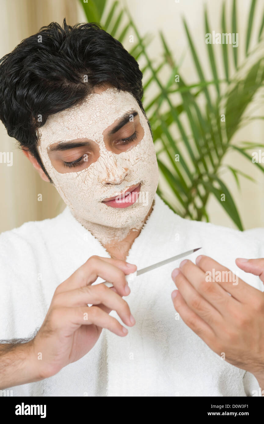 Portrait d'un homme avec un masque facial et de dépôt de ses ongles Banque D'Images