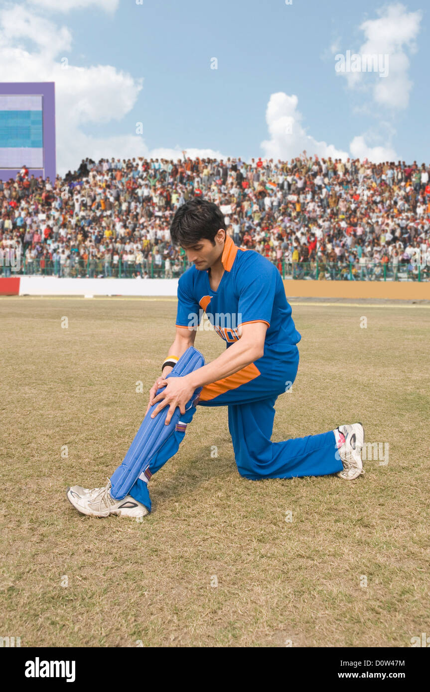 Joueur de cricket de régler son tibia Banque D'Images