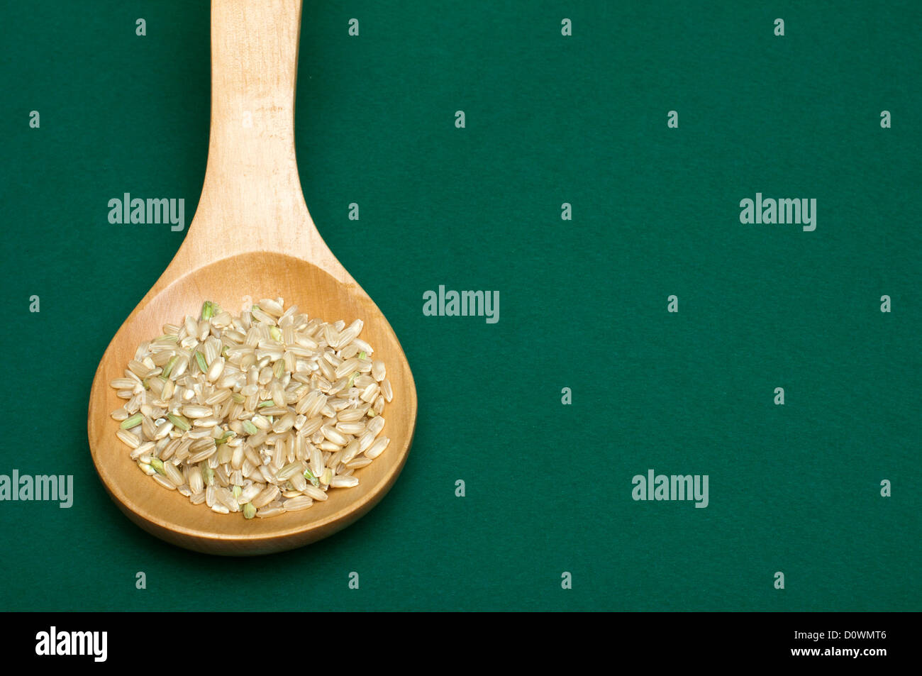 Partie intégrante du riz dans la cuillère en bois sur fond vert. Spice de copie Banque D'Images