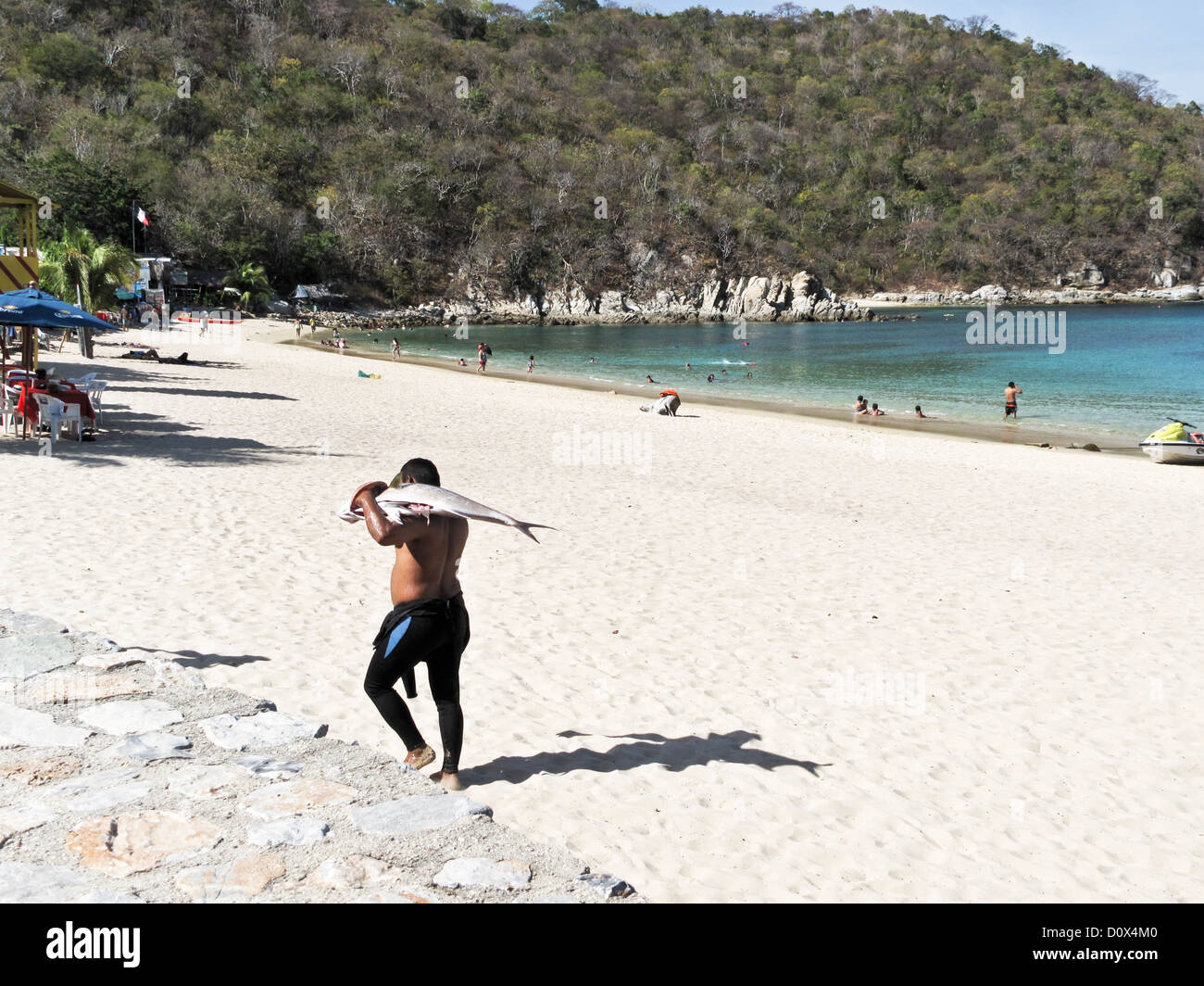 Mexican Homme Porte Des Poissons Fraichement Peches Dans Lensemble Tandis Que Les Amateurs De Plage De Sable Blanc Profitez De Bains De Mer Dans Le Calme Mexican Homme Porte Des Poissons Fraichement Peches Dans Lensemble Tandis Que Les Amateurs De Plage De Sable Blanc Profitez De Bains De Mer Dans Le Calme