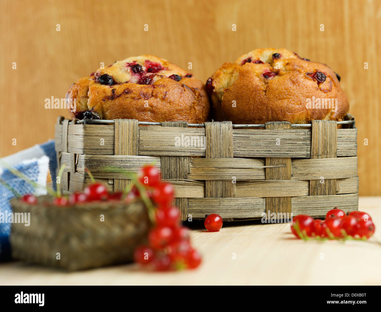 Muffins à la groseille, dans un panier tressé, avec un tas de groseilles rouges devant elle, en haut d'une cuisine en bois board Banque D'Images