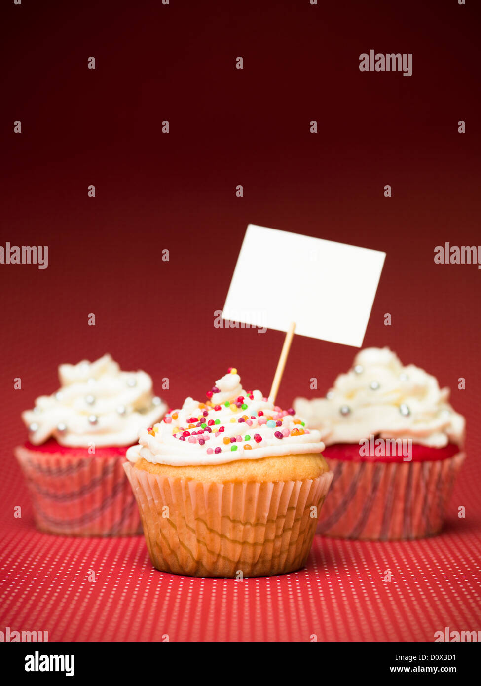 Muffins aux couleurs bonbon sur la table rouge avec des points blancs et de signe vierge fond rouge dégradé Banque D'Images