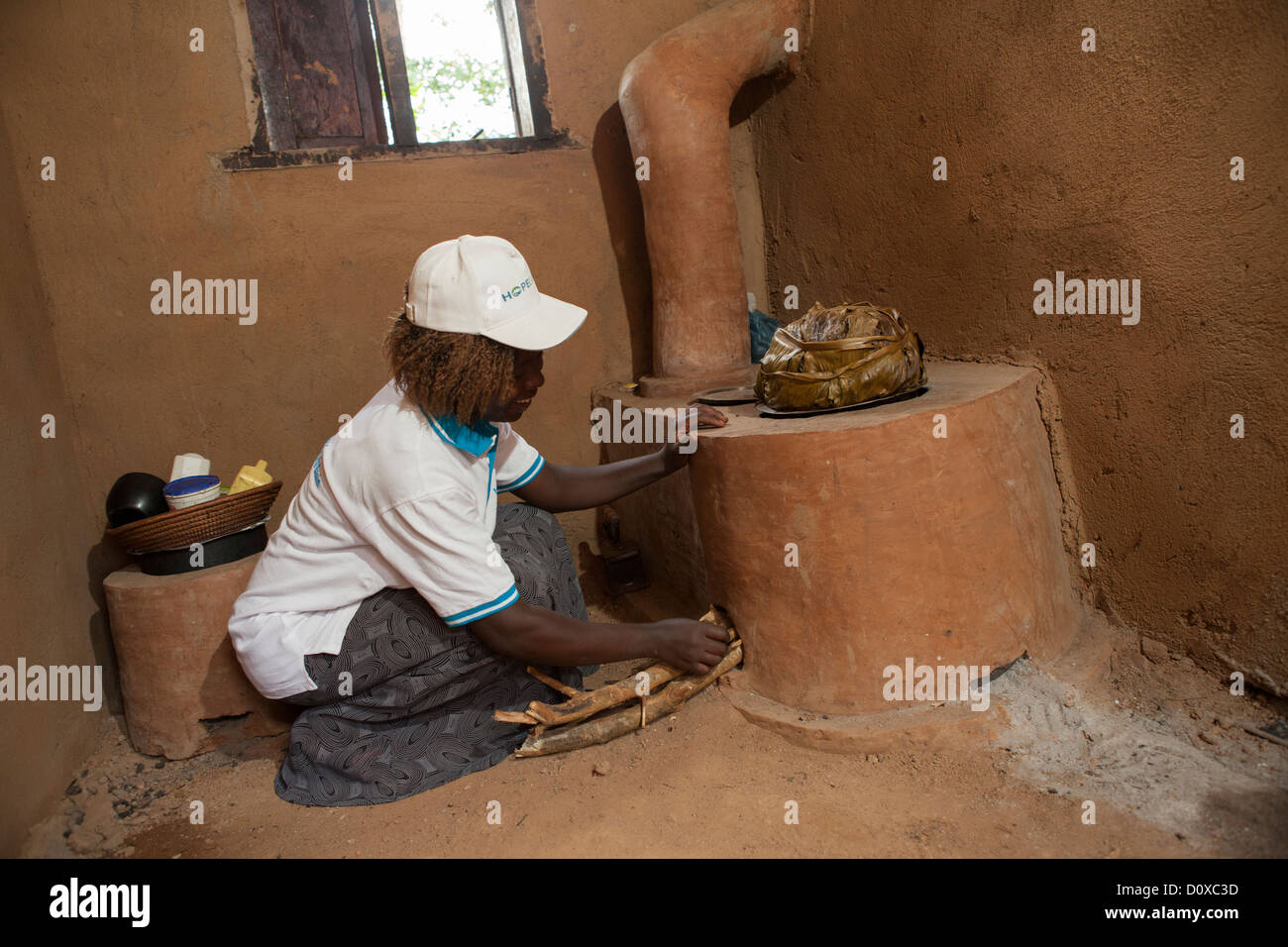 Une femme utilise une cuisinière à économie d'énergie dans sa cuisine sur Bussi Island, Ouganda, Afrique de l'Est Banque D'Images