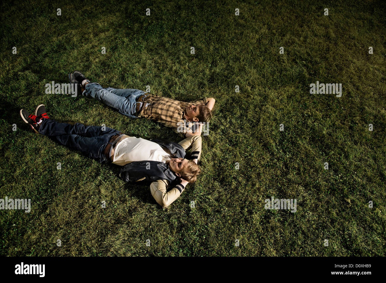 Deux jeunes hommes couchés sur l'herbe la nuit, high angle Banque D'Images