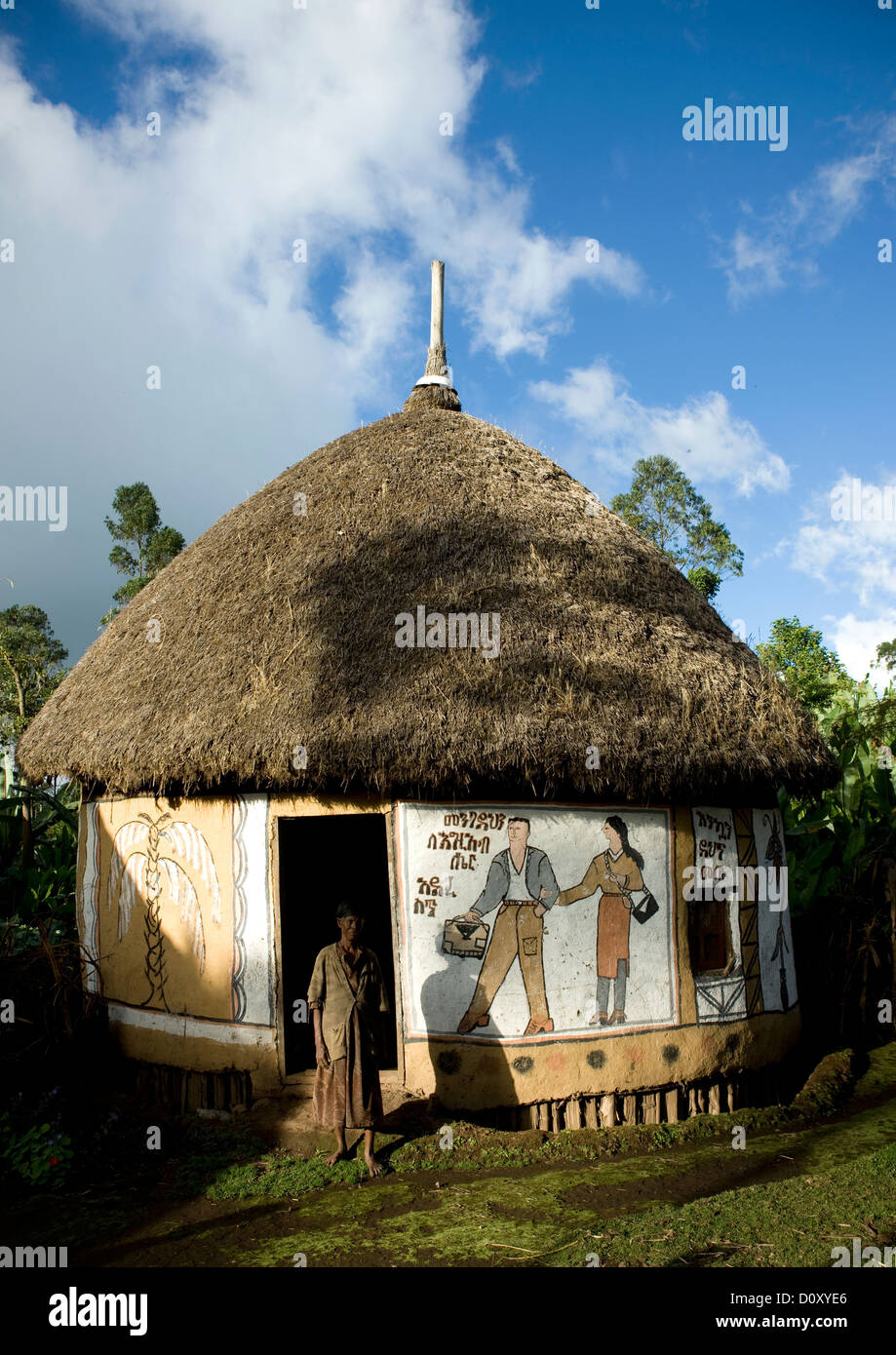 Femme debout à l'extérieur d'une traditionnellement peints Hosanna House, Ethiopie Banque D'Images