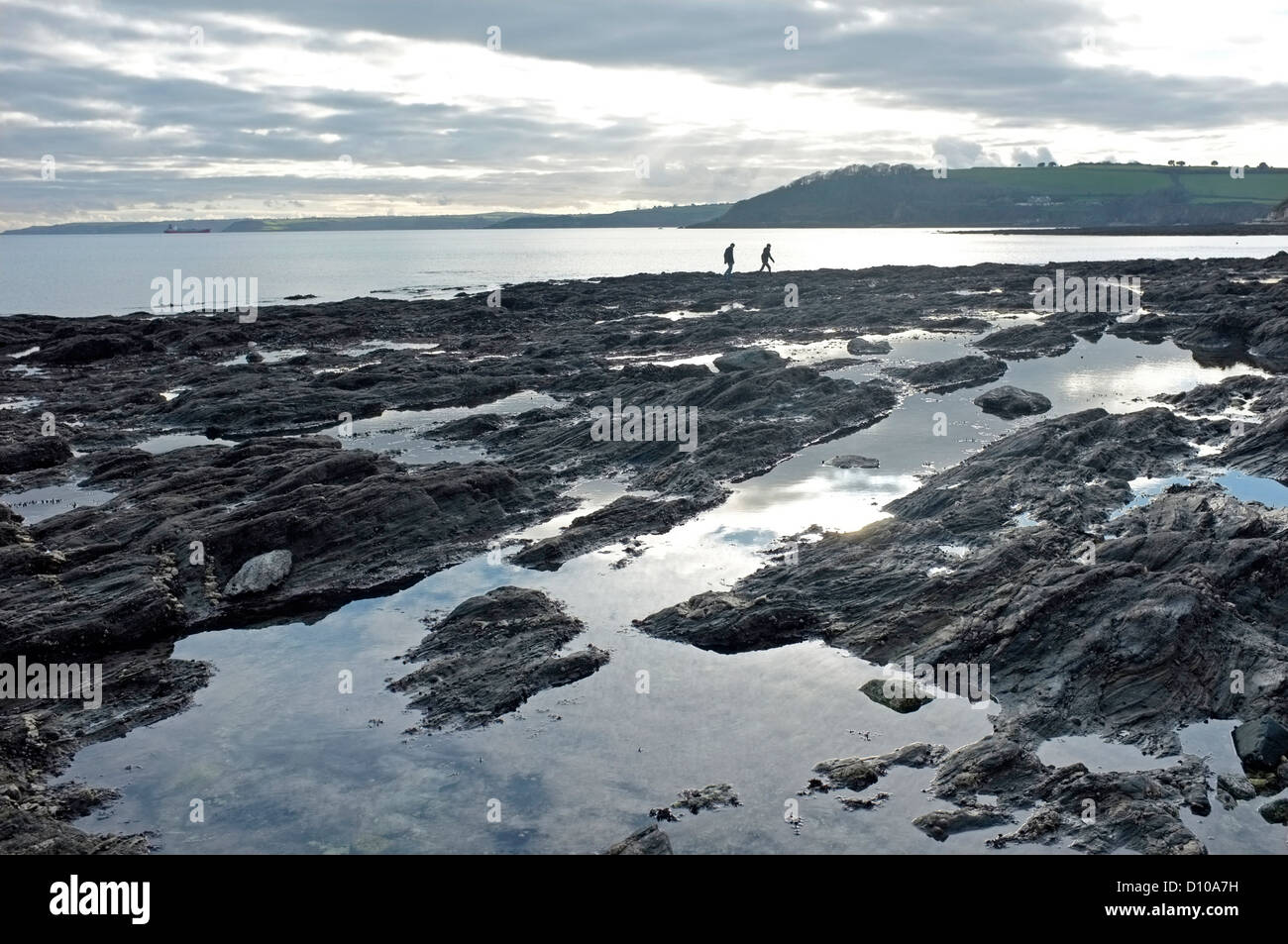 Deux personnes marchant le long d'une plage vide la plage Gyllyngvase à Falmouth, Cornwall, UK en hiver. Banque D'Images