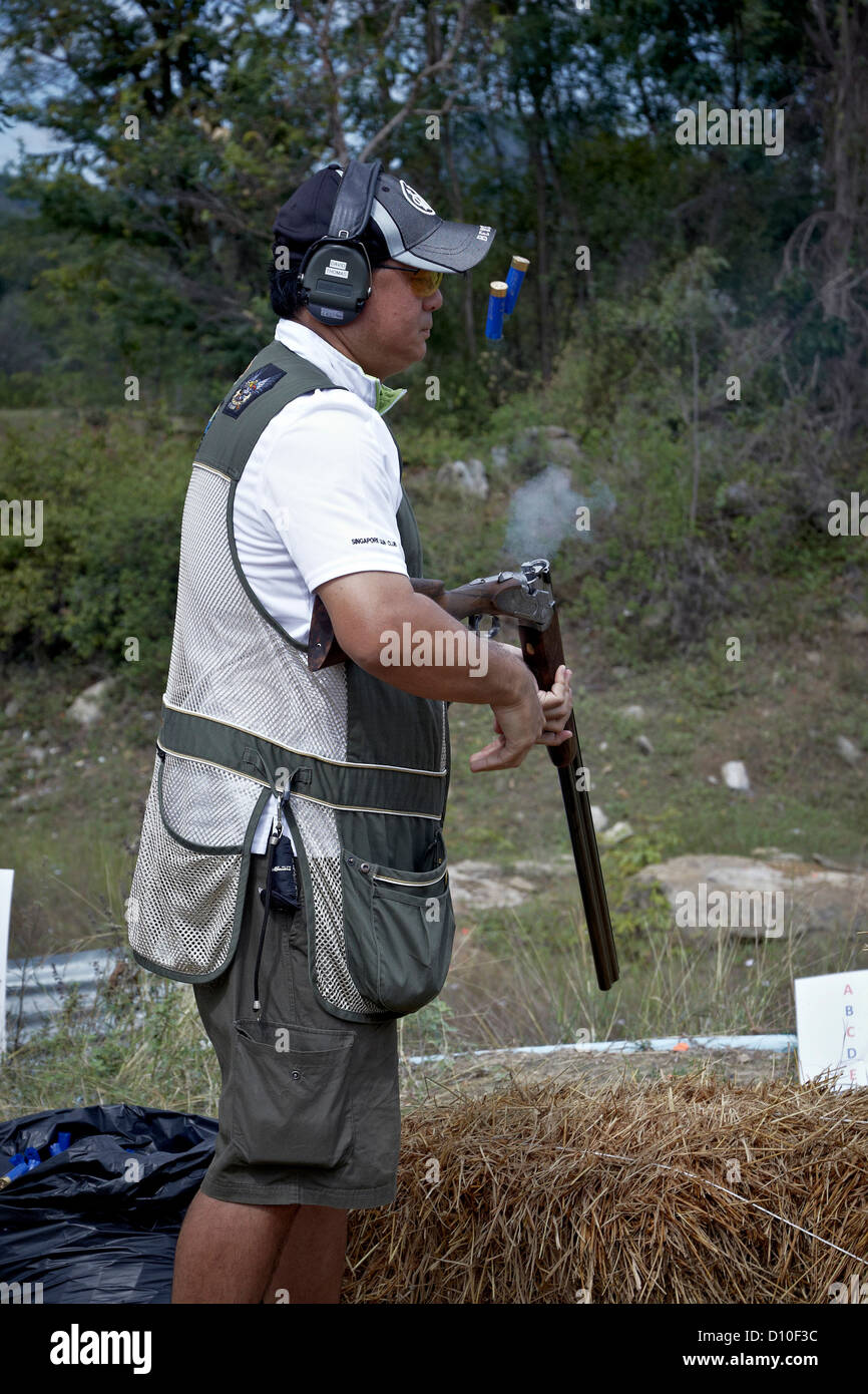 Tireur de pigeon en argile éjectant les cartouches usagées du fusil de chasse Banque D'Images