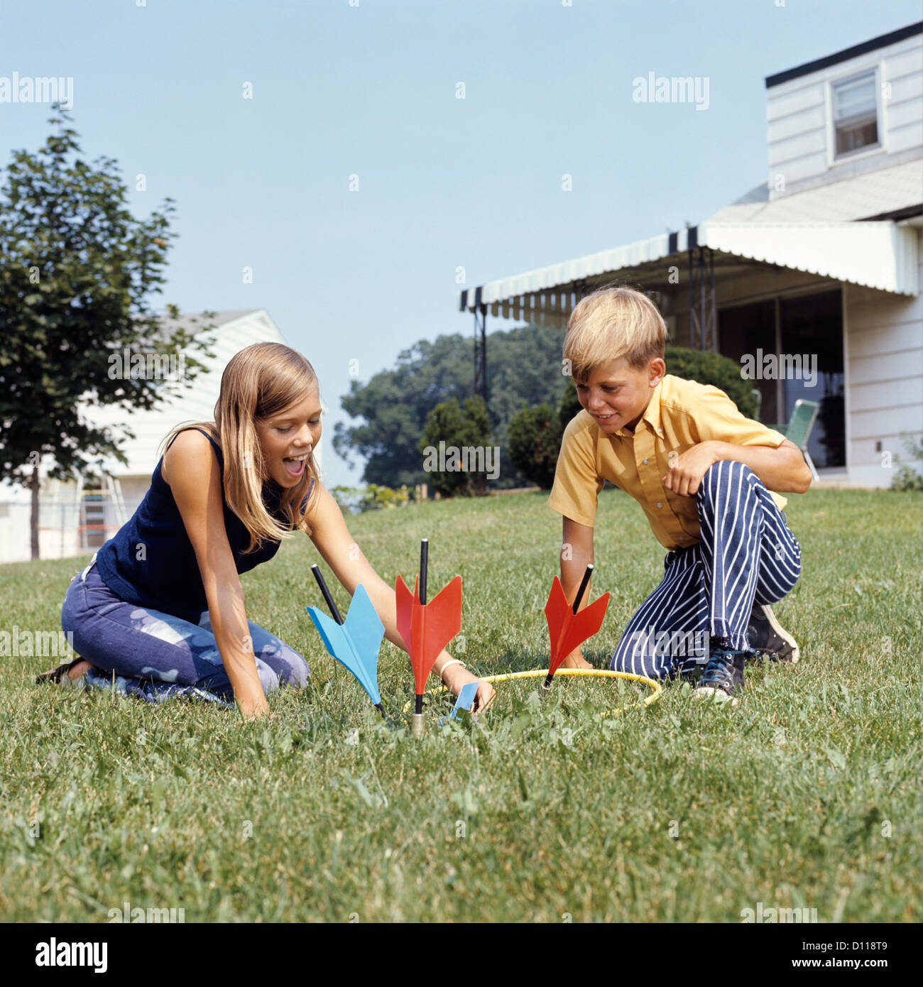 1970 Garçon Fille jouant le jeu de fléchettes de pelouse à l'arrière-cour Banque D'Images