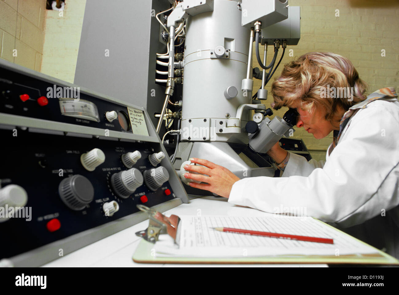 1970 Technicien de laboratoire à l'aide de MICROSCOPE ÉLECTRONIQUE FEMME Banque D'Images