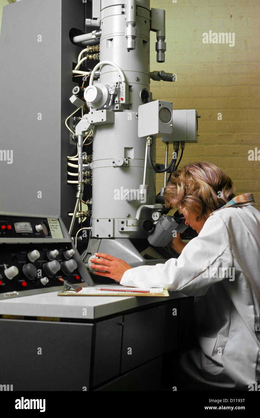 1970 1970 TECHNICIEN LABORATOIRE RÉTRO Femme à l'aide de MICROSCOPE ÉLECTRONIQUE Banque D'Images