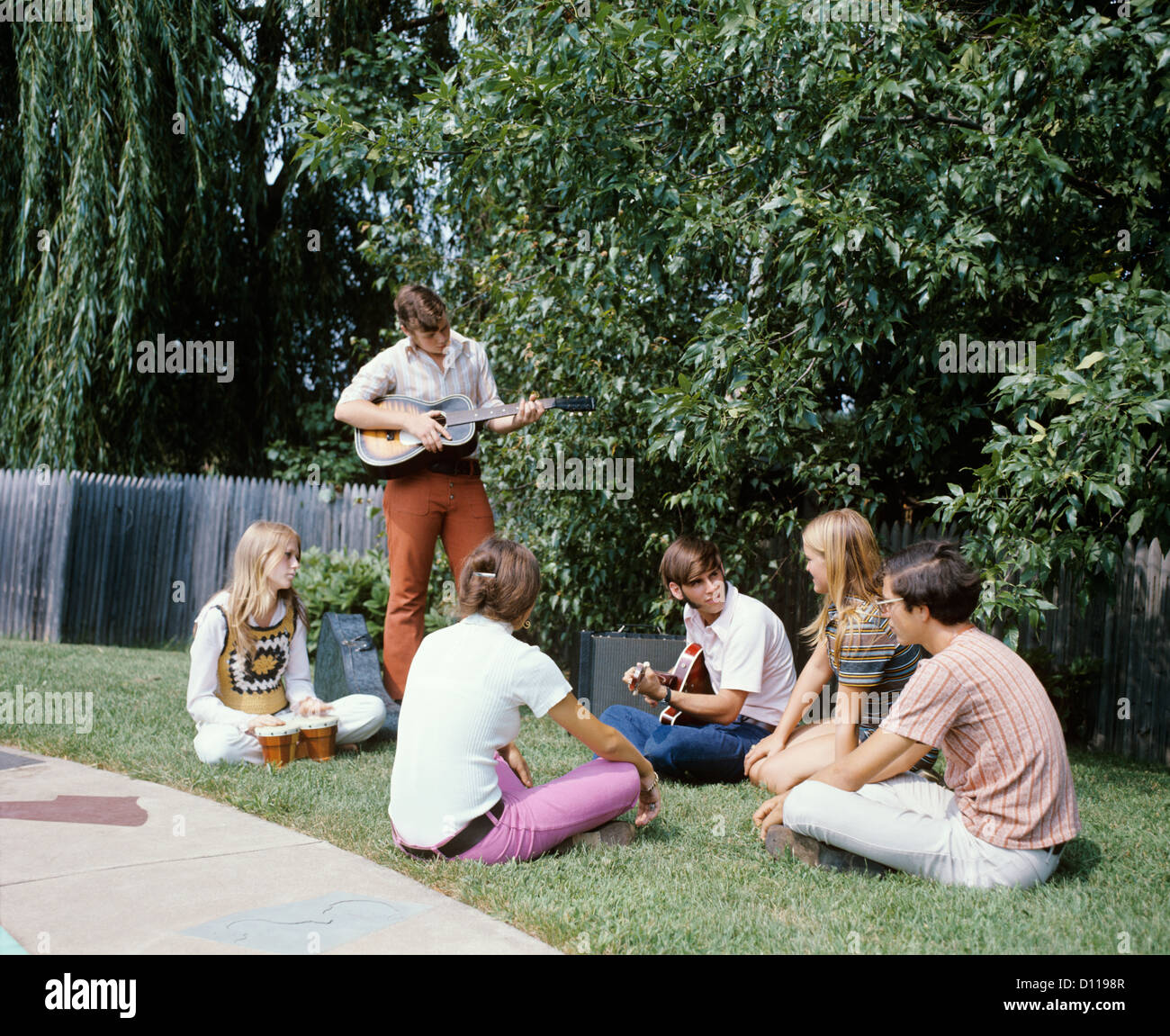 1970 groupe 6 les adolescents à l'extérieur Jardin Garçons Filles JOUEURS DE GUITARE BONGO DRUMS Banque D'Images