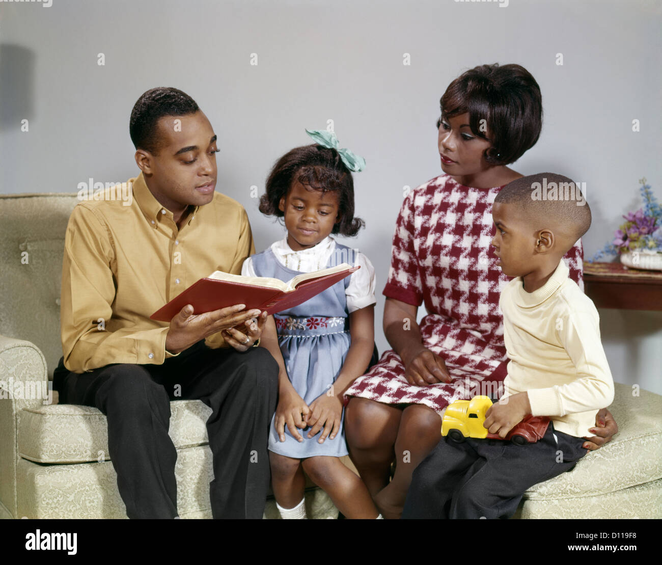 1960 AFRICAN AMERICAN FATHER LA LECTURE D'UN LIVRE DE FAMILLE Banque D'Images