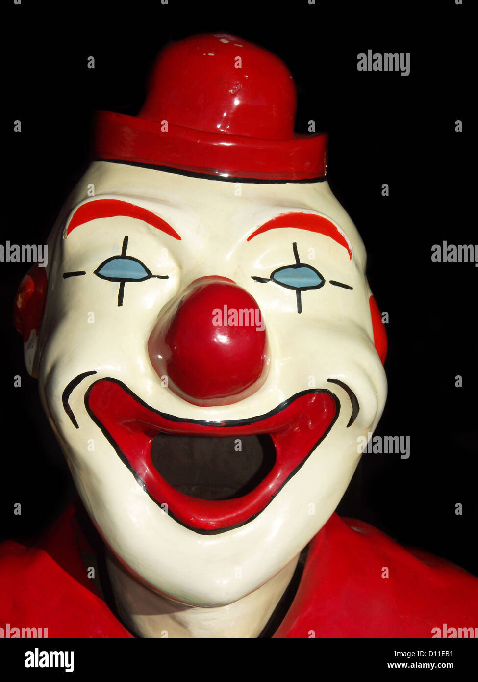 Riant visage blanc de clown sideshow avec nez rouge, la bouche et le chapeau - sur un fond noir Banque D'Images