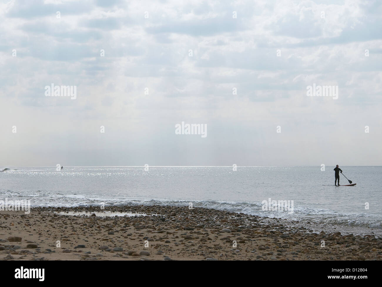 Un couple de stand up paddleboarders au large de la plage de Montauk pendant les heures tôt le matin à la plage des plaines de fossé. Banque D'Images