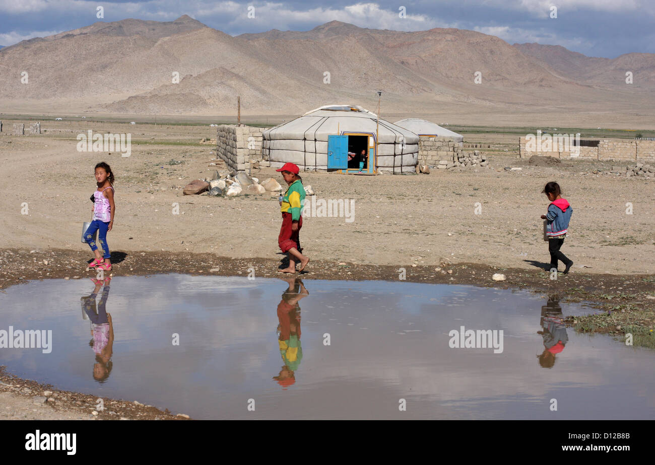 Les enfants passent devant une flaque à Khovd, W. Mongolie Banque D'Images