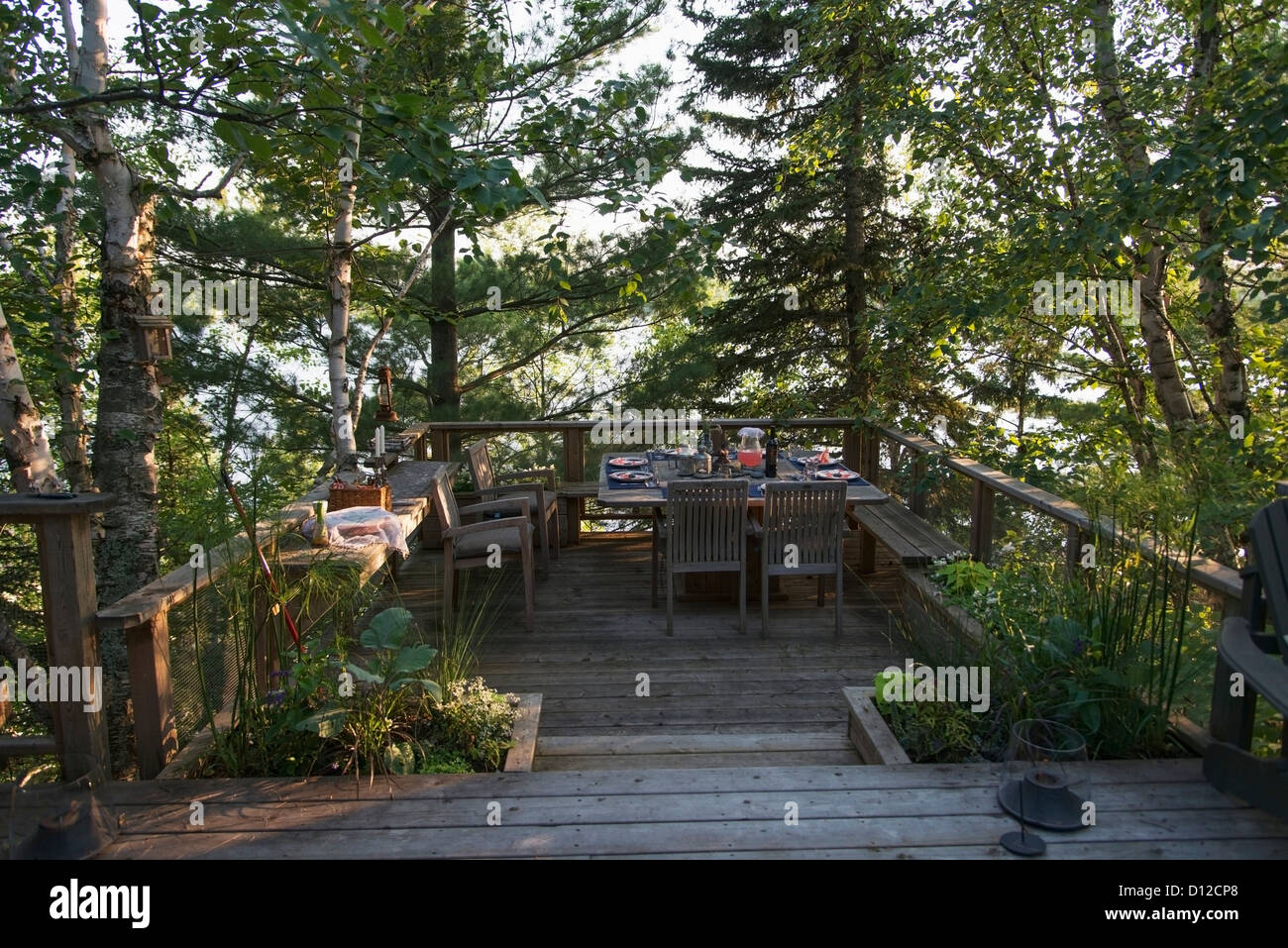 Un set de table pour un repas sur une terrasse en bois entourée d'arbres d'un lac ; le lac des Bois Ontario Canada Banque D'Images