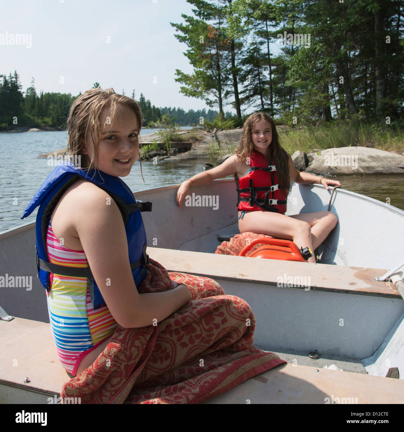 Les filles de remorquage assis dans un bateau par le bord d'un lac, le lac des Bois Ontario Canada Banque D'Images