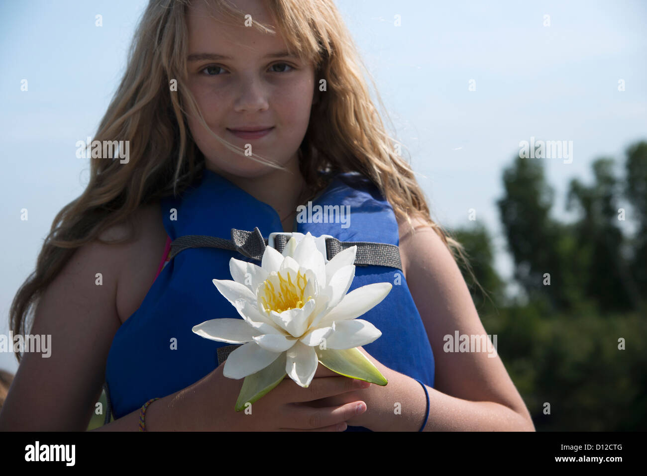 Une jeune fille portant un gilet est titulaire d'une fleur blanche, Kenora (Ontario) Canada Banque D'Images