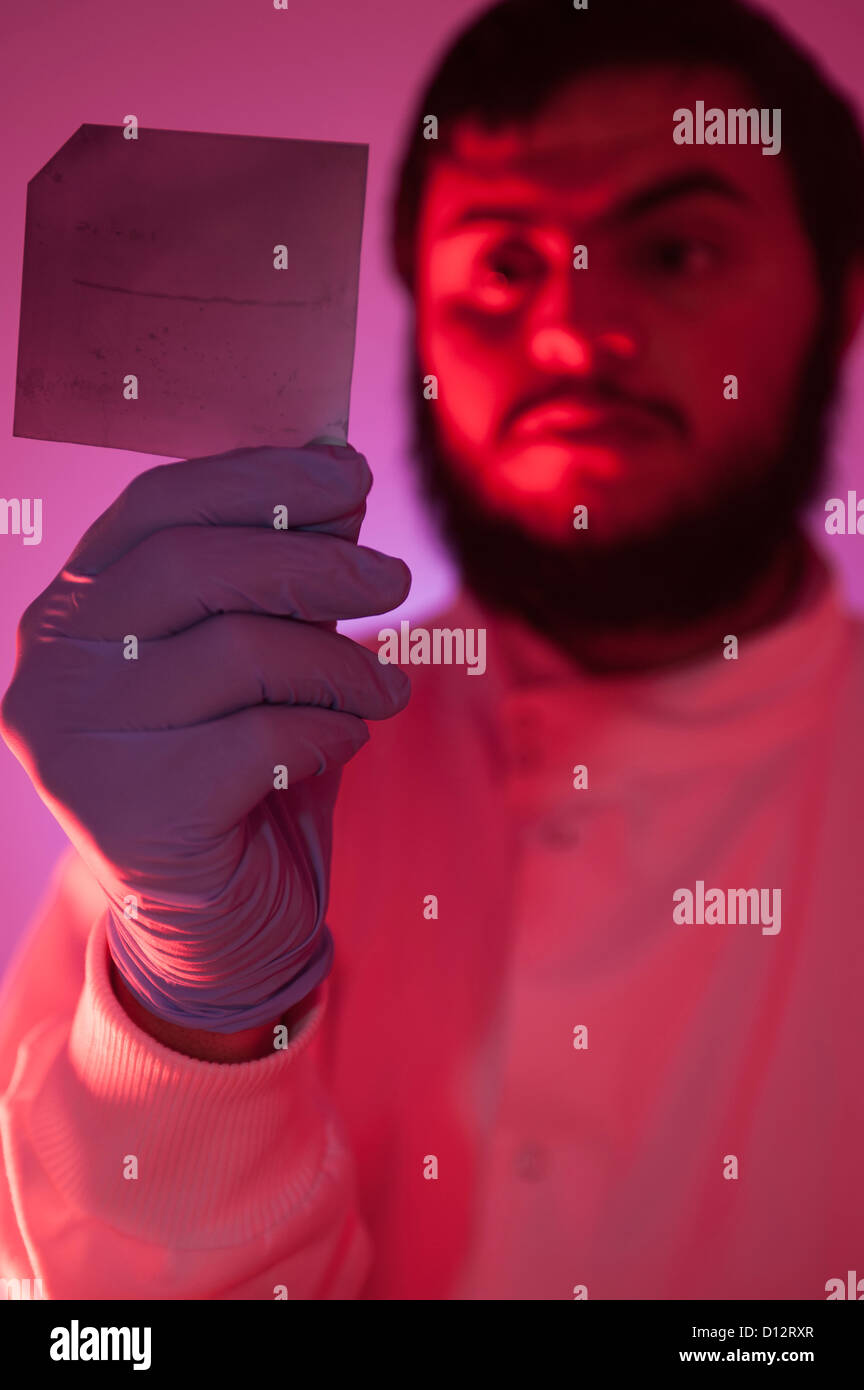 Asian male scientist, technicien ou chercheur examine une diapositive de l'ADN par la lumière de l'infrarouge dans darkroom Banque D'Images