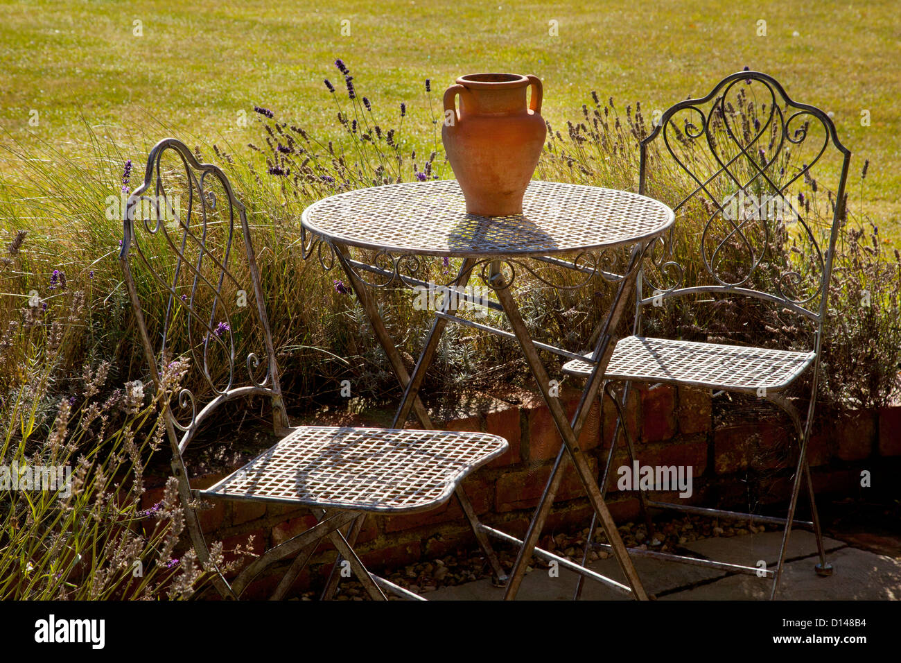 Metal French style mobilier de jardin table et chaises avec pot en terre cuite à l'été jardin Anglais Banque D'Images