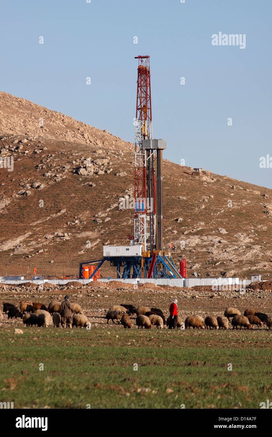 Exploration pétrolière et gazière en plate-forme de forage du site avec des bergers, hommes et femmes ayant tendance moutons en avant. Le Kurdistan irakien, l'Irak Banque D'Images