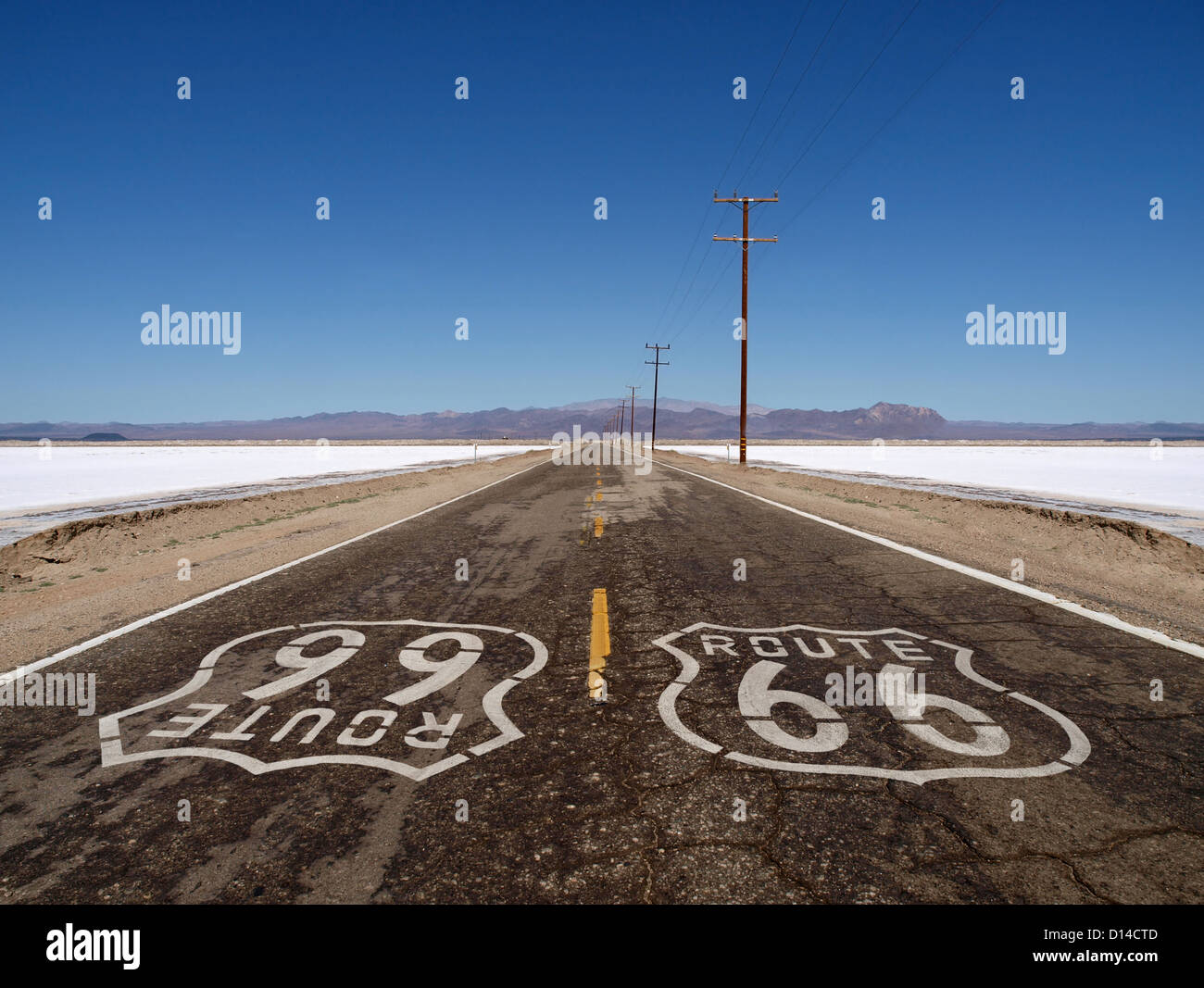 Route 66 sign painted sur désert de Mojave de sel de chaussée sur les routes. Banque D'Images
