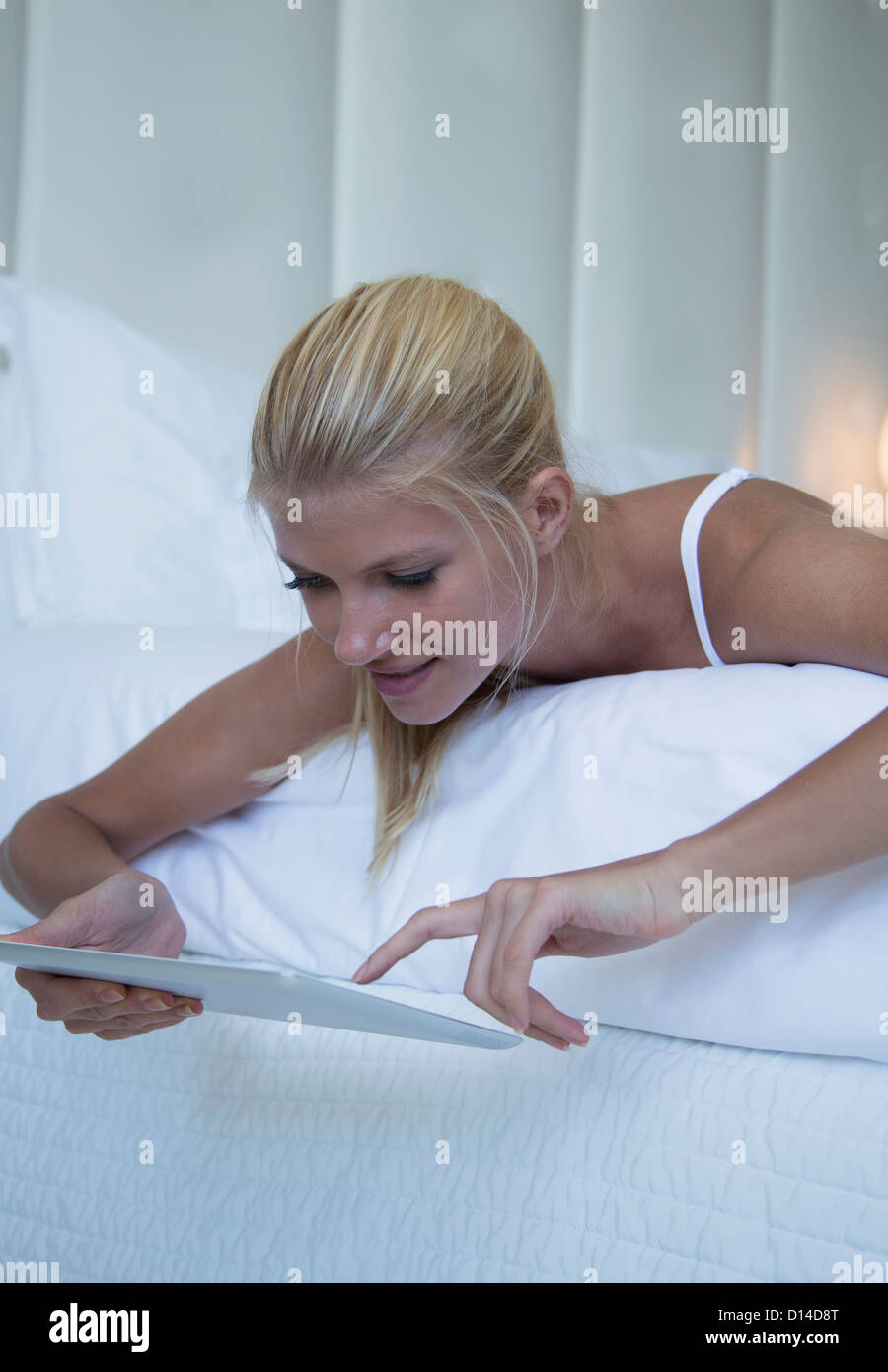 Woman using tablet computer on bed Banque D'Images