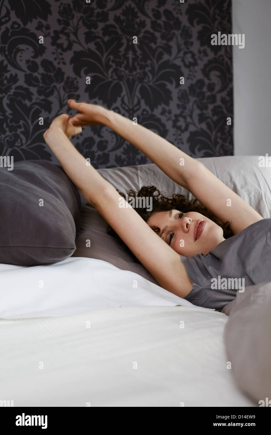Young woman Lying in Bed stretching Banque D'Images