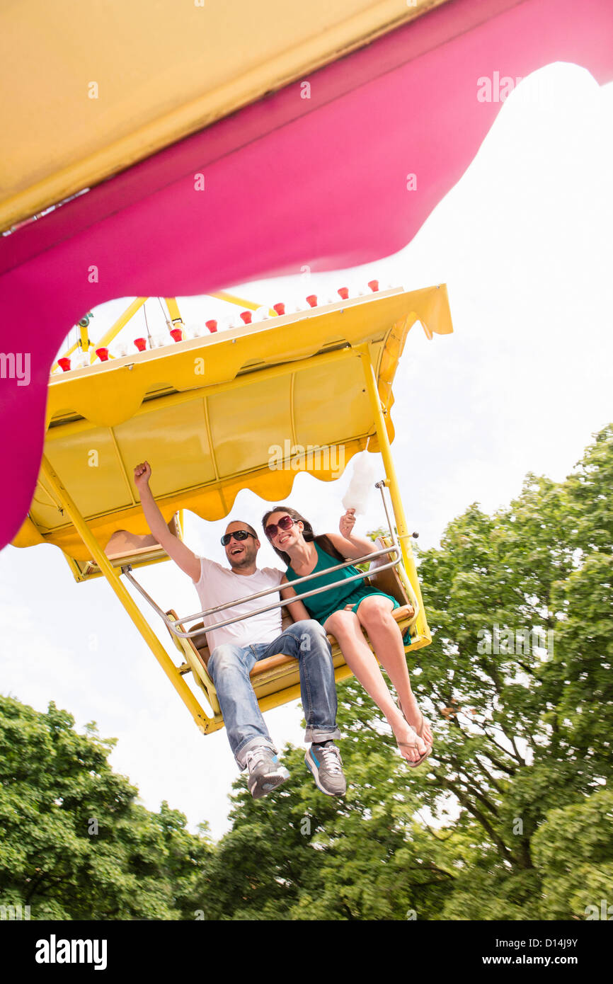 Couple riding amusement park ride Banque D'Images