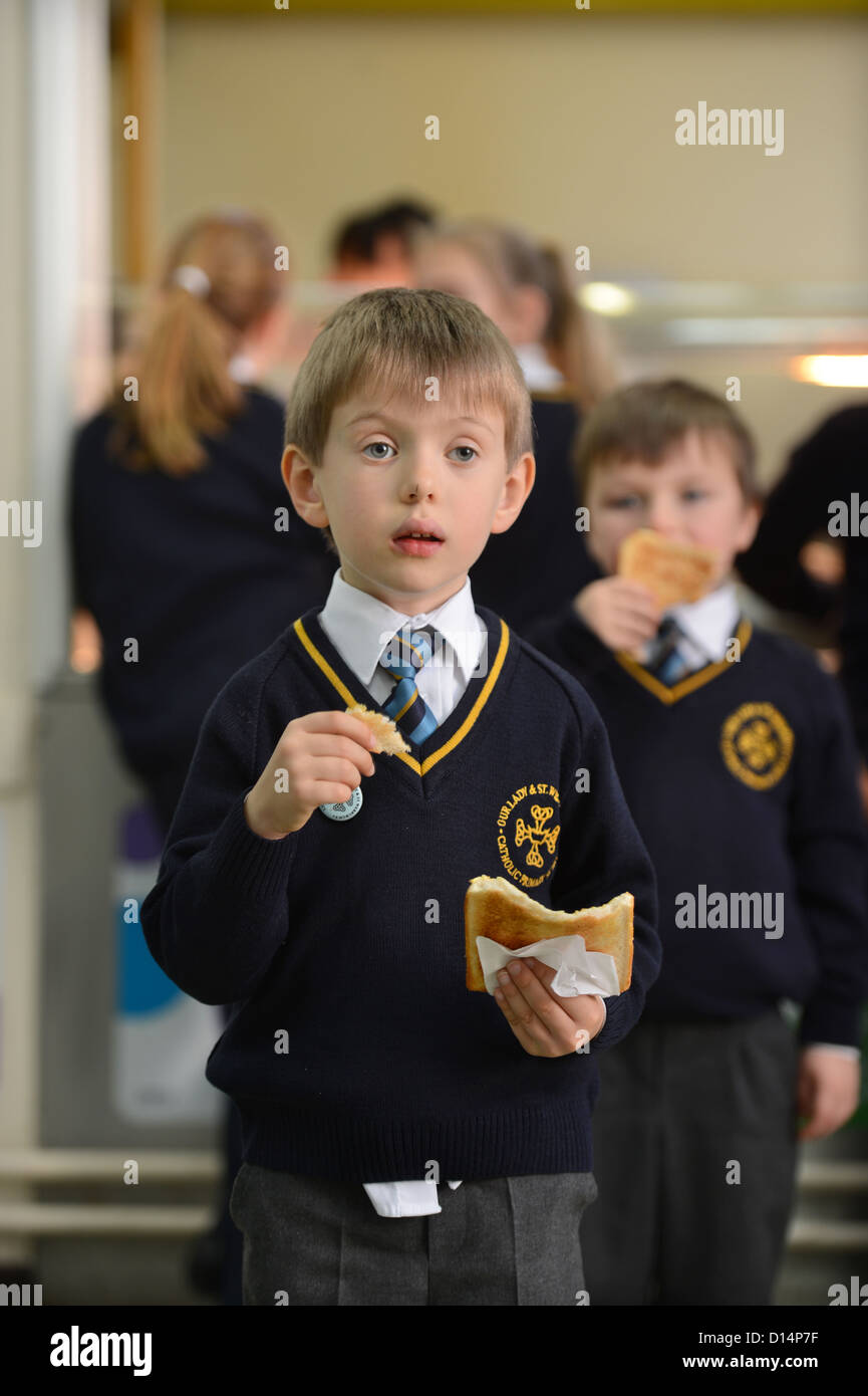 Un écolier eating toast après matin Assemblée générale à Notre Dame et St Werburgh's Catholic Primary School à Newcastle-under-Lyme, St Banque D'Images