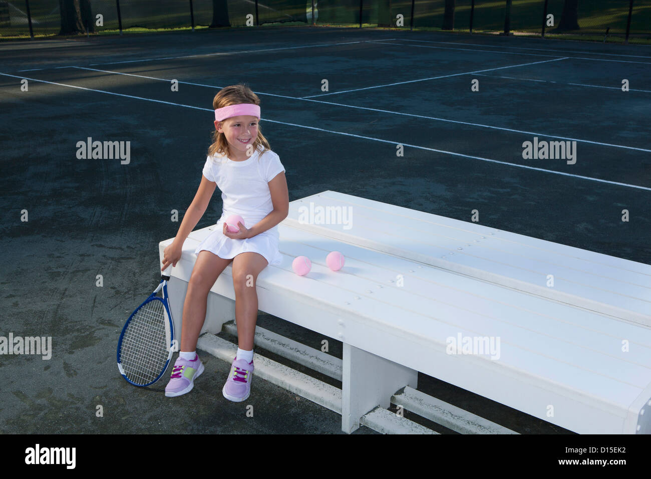 USA, Arizona, Texarkana, Girl (6-7 ans) assis sur un banc et holding tennis racket Banque D'Images