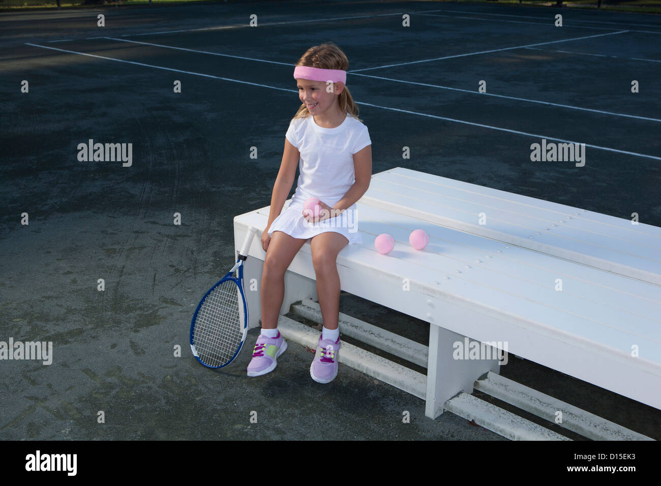 USA, Arizona, Texarkana, Girl (6-7 ans) assis sur un banc et holding tennis racket Banque D'Images