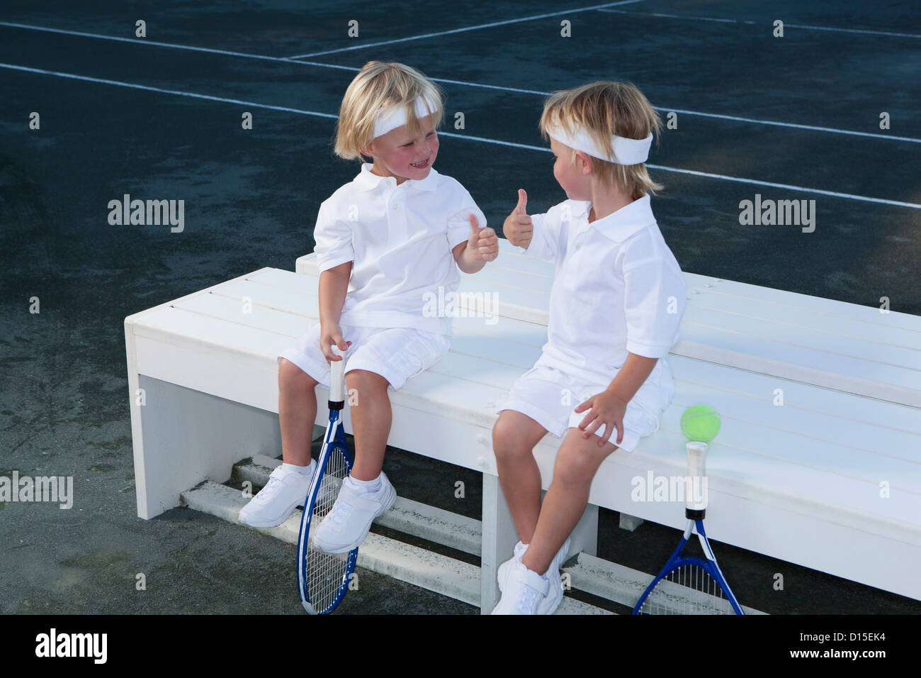 USA, Arizona, Texarkana, deux garçons (2-3 ans) assis sur un banc avec des raquettes de tennis Banque D'Images