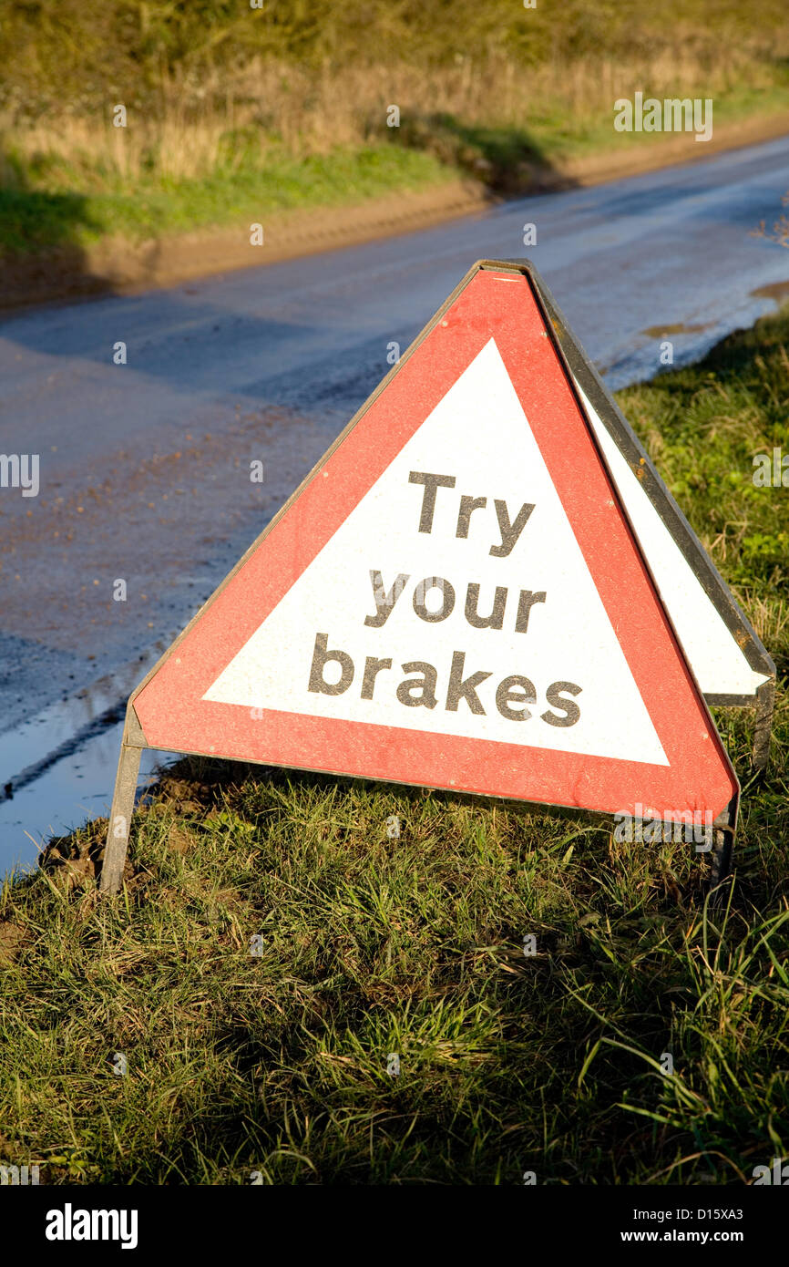 A essayer vos freins avertissement assis sur un bord de l'herbe près d'une route inondée à Norfolk. Banque D'Images