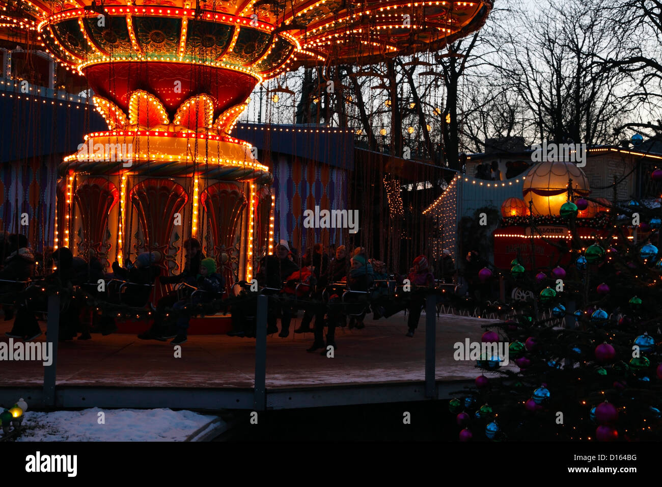 Le carrousel de rotation, les arbres de Noël et des décorations au crépuscule au marché de Noël de la neige recouvrait les jardins de Tivoli, Copenhague, Danemark Banque D'Images