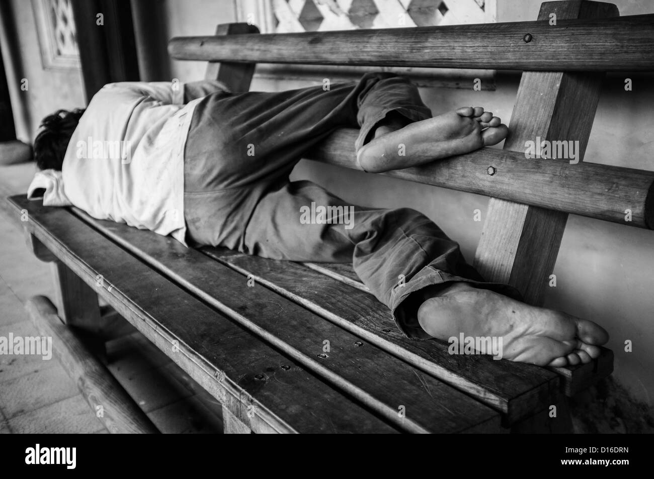 Homme nu dormant sur un banc en bois Banque D'Images