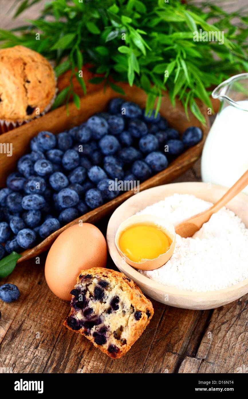 Muffins aux bleuets, d'oeuf, la farine et le lait sur la table en bois Banque D'Images