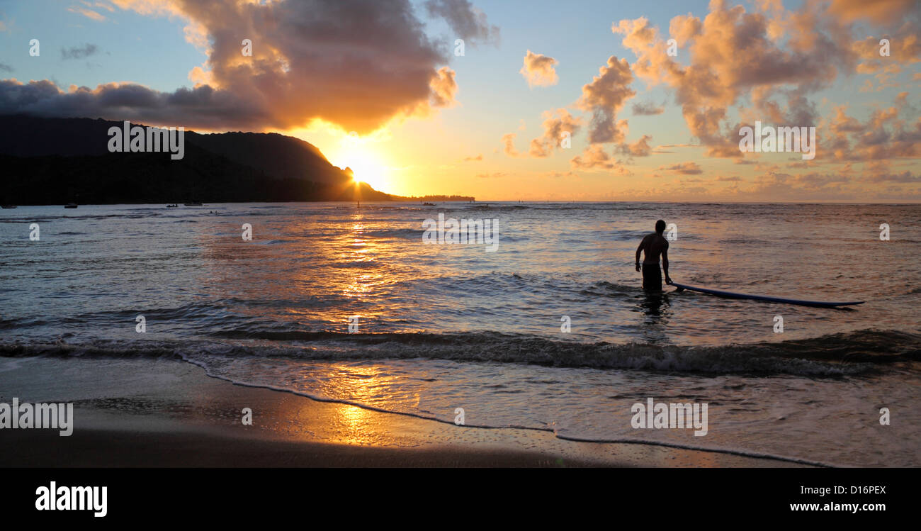 Surfer à Baie d'Hanalei sur Kauai au coucher du soleil Banque D'Images