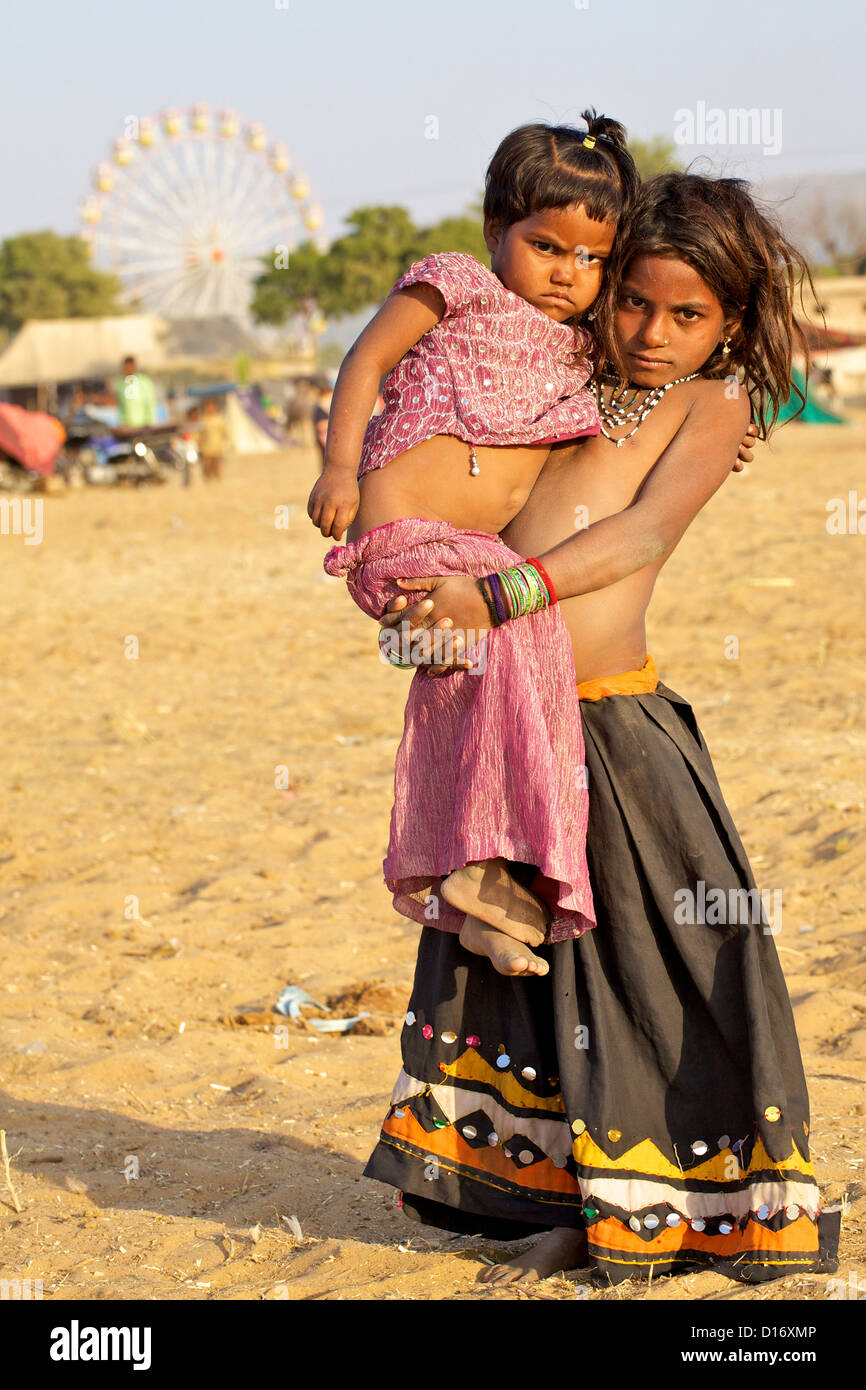 Une jeune fille porte un bébé lors de la foire de Pushkar au Rajasthan, Inde Banque D'Images