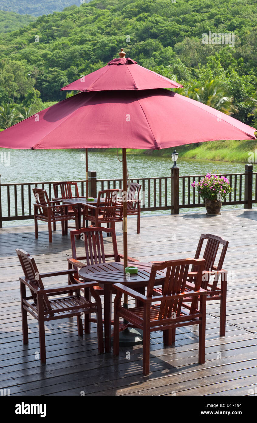 Patio près de la rivière avec tables, chaises et parasol Banque D'Images
