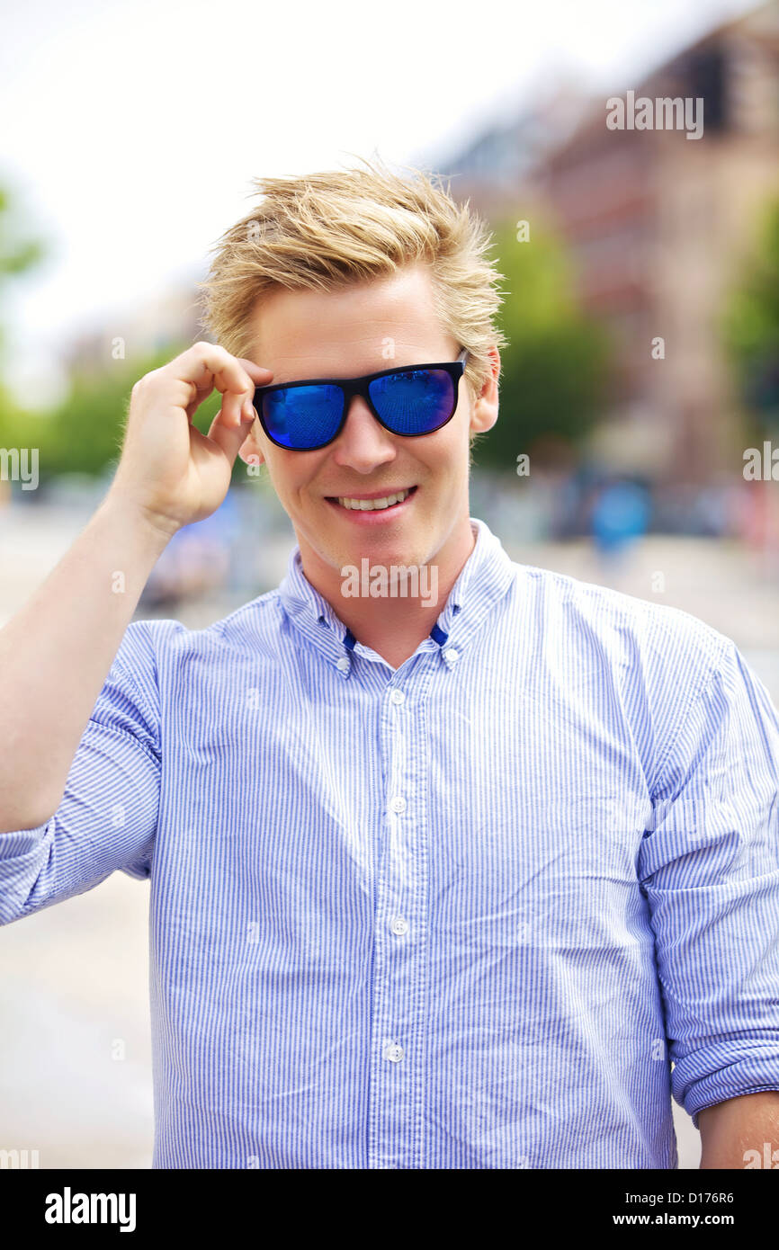 Portrait d'un beau mec cool et à l'extérieur avec ses lunettes de soleil sur Banque D'Images