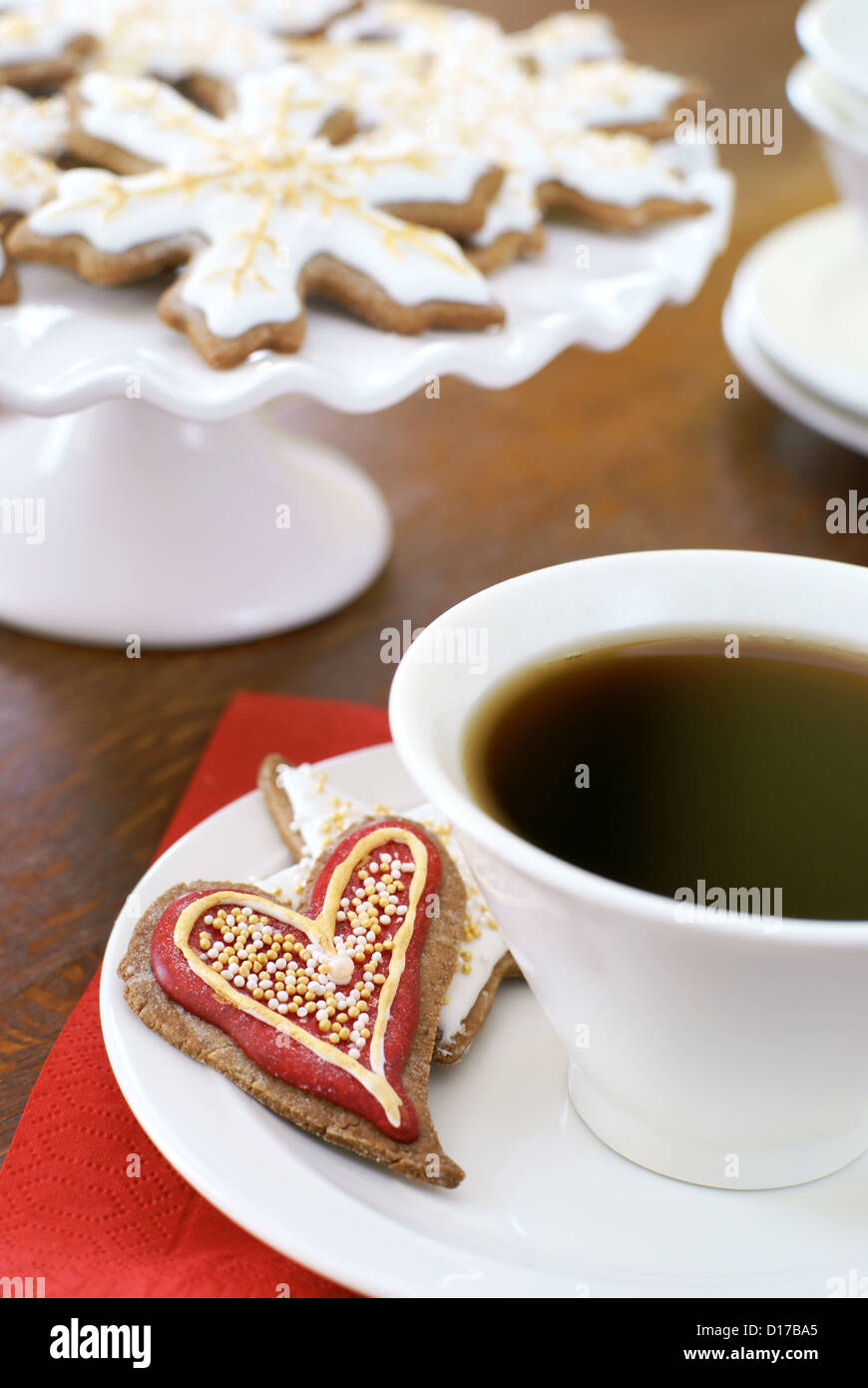 Heart shaped gingerbread cookie, décorée pour Noël, et une tasse de café. Banque D'Images