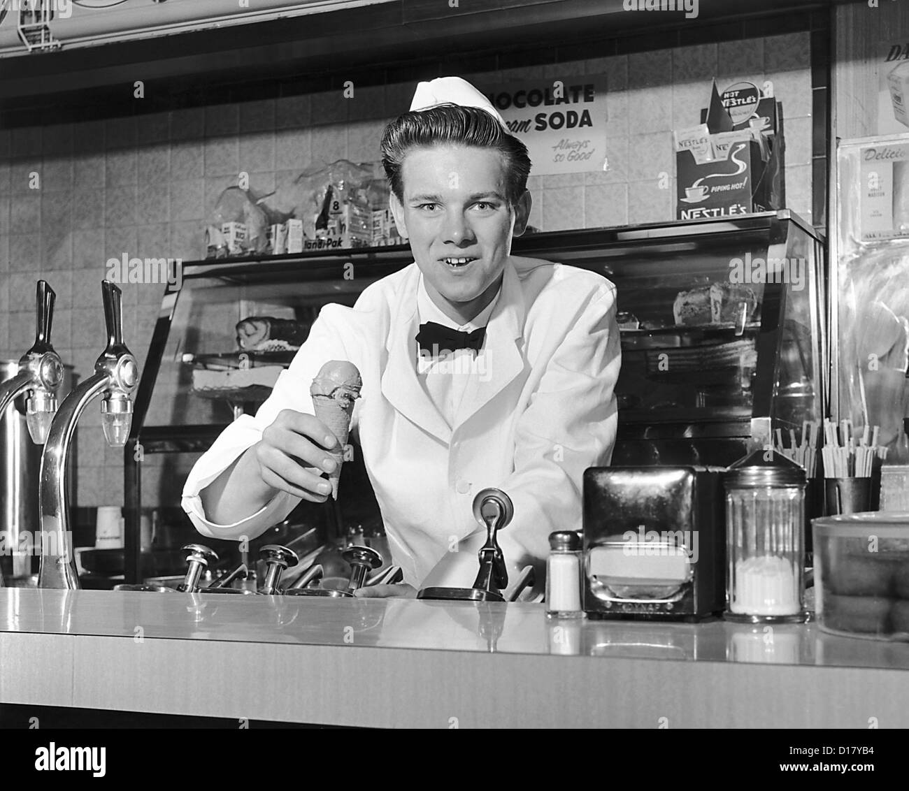 Soda jerk holding ice cream cone Banque D'Images