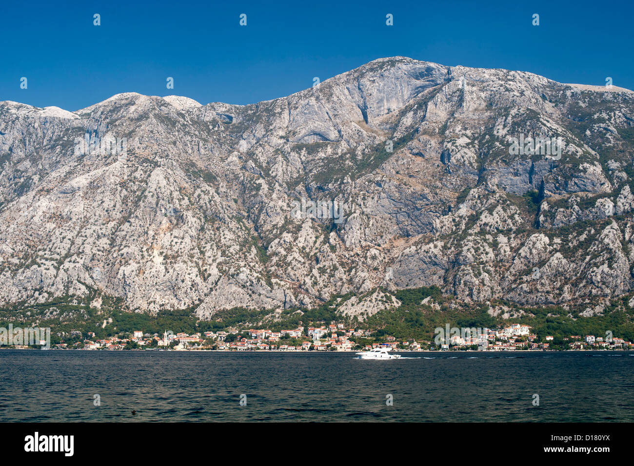 Vue sur les montagnes et les maisons bordant le bord de la baie de Kotor au Monténégro. Banque D'Images