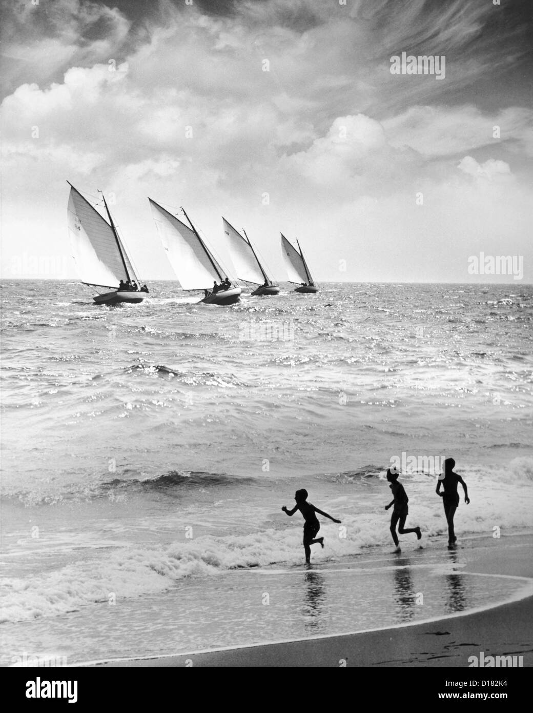 Les enfants courent le long du littoral de plage, voiliers à distance Banque D'Images